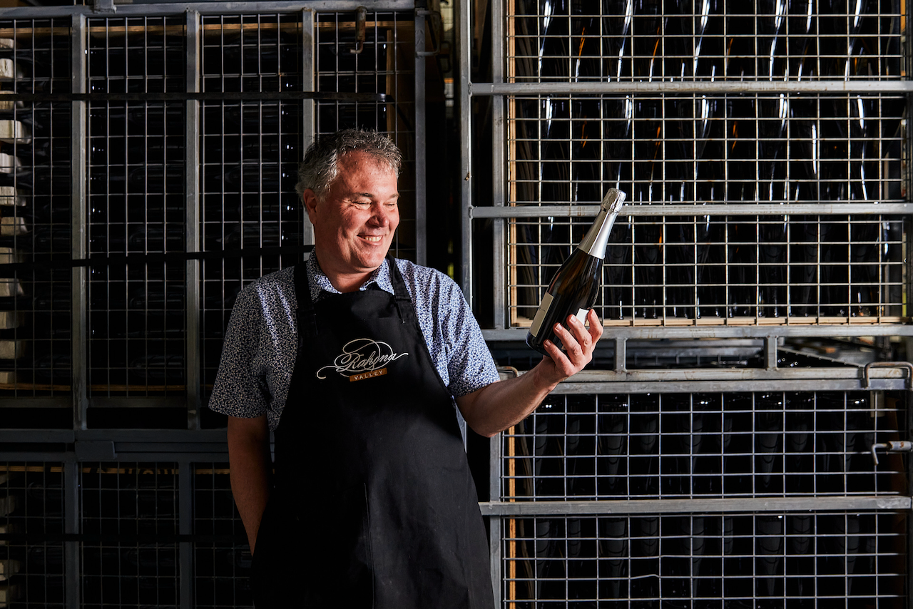 A man in the wine cellar inspecting a wine bottle 